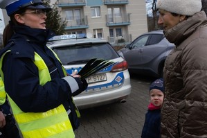 policjantka ruchu drogowego trzymająca odblaski w ręce i rozmawiająca z pieszymi