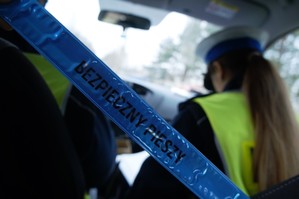 odblask z napisem bezpieczny pieszy na tle policjantów ruchu drogowego w radiowozie