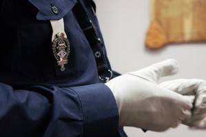 zdjęcie przedstawia: zbliżenie na emblemat ruchu drogowego i białe rękawiczki policjanta