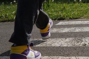 zdjęcie przedstawia: zbliżenie na buty osoby przechodzącej przez przejście dla pieszych