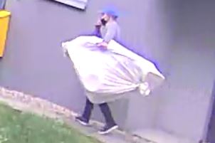 Na zdjęciu mężczyzna podejrzewany o kradzież wózka dziecięcego. Męzczyzna trzyma w rękach duży przedmiot zakryty białym materiałem.
