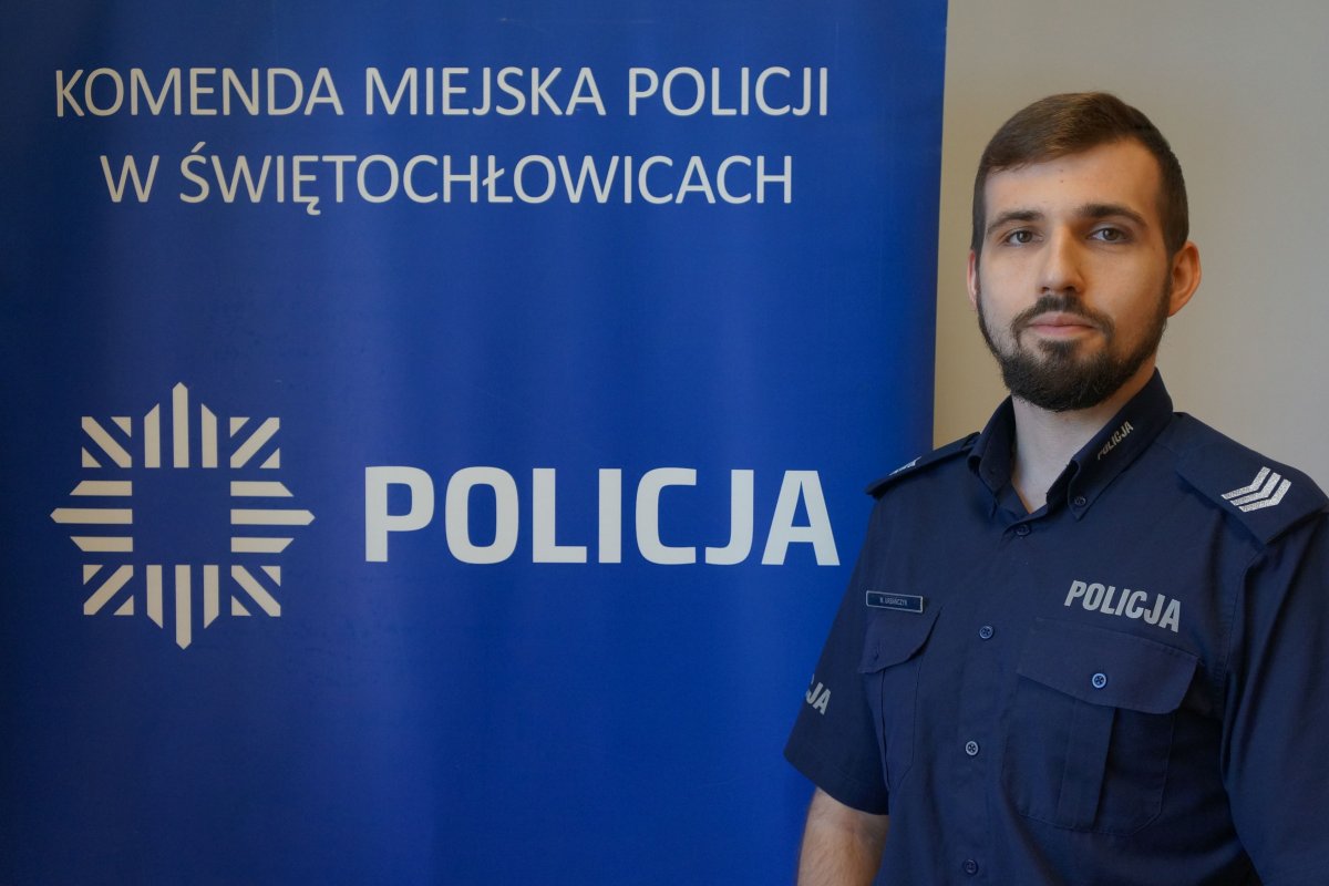 Dzielnicowy sierż. szt. Mateusz Urbańczyk na tle baneru z napisem Policja