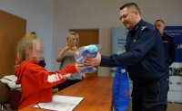 Na zdjęciu dziewczynka po lewej, po prawej Komendant insp. Andrzej Brzozowski wręczający mini maskotkę śląskiej policji - Sznupka.
