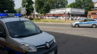 radiowóz straży miejskiej i policji na tle wiernych