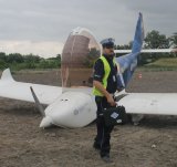 Funkcjonariusz policji na tle Samolotu dwumiejscowy po awaryjnym lądowaniu na nieużytkach
