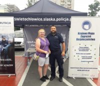 Policjant pozujący do zdjęcia z kobietą przy mobilnym stanowisku