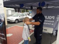 Policjant zakłada na szyję dziewczynce gadżet w postaci smyczy