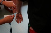 śledcza podczas rozkuwania zatrzymanemu kajdanek