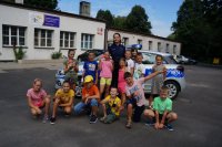 Dzieci biorące udział w półkoloniach w MDK w Świętochłowicach z policjantką ze świętochłowickie komendy na tle MDK