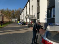 Realizator z kamerą podczas nagrywania policjantów drogówki w czasie wchodzenia do radiowozu na tle budynku świętochłowickiej komendy