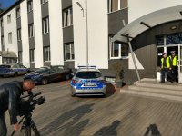 Realizator z kamerą podczas nagrywania policjantów drogówki w czasie wchodzenia do radiowozu na tle budynku świętochłowickiej komendy