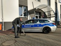 Realizator z kamerą podczas nagrywania policjantów drogówki w czasie siedzenia w radiowozie na tle budynku świętochłowickiej komendy