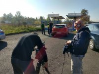 Na pierwszym planie ekipa TVP1 w trakcie nagrania. w tle Policjanci z Wydziału Ruchu Drogowego KMP Świętochłowice podczas wykonywania czynności służbowych po zatrzymaniu pojazdu do kontroli.