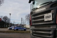 ciężarówka z napisem odpady, w tle zaparkowane dwa policyjne radiowozy