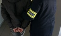 policjant z wydziału krymianlnego idący z mężczyzną zatrzymanym zakutym w kajdaniki