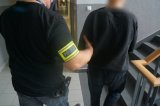 zatrzymany mężczyzna zakuty w kajdanki w trakcie doprowadzenia do jednostki policji prze policjanta z wydziału kryminalnego