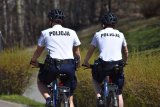 policjanci jadący na rowerze leśną ścieżką