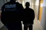 zatrzymany mężczyzna zakuty w kajdanki podczas doprowadzeni do jednostki policji