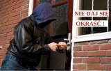 Na zdjęciu osoba ubrana na ciemno z łomem w rękach próbuje włamać się do mieszkania. Po lewej stronie czerwony napis na białym tle Nie daj się okraść!