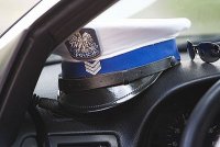 czapka policyjna z białym otokiem i orłem na przodzie wewnątrz radiowozu
