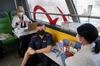 Na zdjęciu wnętrze autobusu. Na zdjęciu widać mundurowego w trakcie oczekiwania na pobranie krwi oraz dwie pracownice Regionalnego Centrum Krwiodawstwa i Krwiolecznictwa w Katowicach