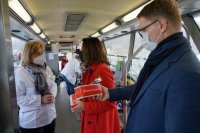 Na zdjęciu wnętrze autobusu. Na zdjęciu widać zastępcę szefa świętochłowickiej Policji oraz Prezydenta Miasta Świętochłowice w chwili odbioru z rąk pracownicy Regionalnego Centrum Krwiodawstwa i Krwiolecznictwa w Katowicach słodkich pakietów po oddaniu krwi