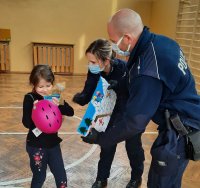 Na zdjęciu policjant wraz z  policjantką wreczają nagrodę uczennicy pierwszej klasy