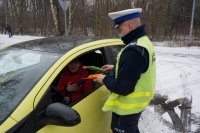 policjant z drogówki w trakcie wręczania kwiatka i życzeń yczestniczce ruchu drogowego z okazji święta kobiet