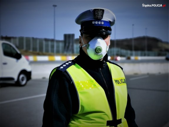 zdjęcie policjanta zwydziału ruchu drogowego  z maseczką na twarzy  w trakcie pełnionej służby