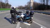 Na zdjęciu policjant z drogówki stojący obok dwóch policyjnych motocykli