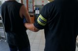 Na zdjęciu nieumundurowany policjant prowadzi zatrzymanego mężczyznę zakutego w kajdanki