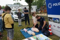 Na zdjęciu mundurowy prowadzi pokaz pierwszej pomocy na fantomie, wokół niego widać policjantkę oraz uczestników festynu przyglądających się czynnością wykonywanym przez policjanta