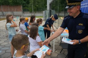 Na zdjęciu widać mundurowych który rozdają dzieciom drobne upomiki