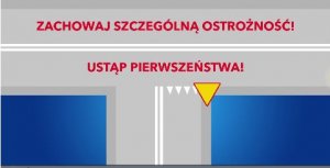 Na zdjęciu skrzyżowanie z drogą podporzadkowaną przy której ustawiony znak ustąp pirwszeństwa przejazdu. Powyżej czerwony napis zachowaj szczególną ostrożność. Ustąp pierwszeństwa przejazdu.