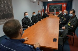 Na zdjęciu  policjant z drogowki w trakcie omawiania przepisów obowiązujących w ruchu drogowym podczas spotkania ze strażakami