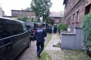 Na zdjęciu widać umundurowanego policjanta idącego w kierunku funkcjonariuszy Samodzielnego Pododdziału Kontrterorystycznego Policji celem uzgadniania taktyki działania podczas prowadzonej interwencji