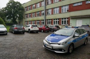 Na zdjęciu radiowóz na tle budynku jednej ze świętochłowickiej szkoły