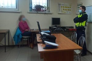 Na zdjeciu policjant z drogówki w trakcie prowadzenia wykładu o zasadach bezpieczeństwa w ruchu drogowych. Na zdjeciu widac siedzaca przy stoliku jedną z kursantek