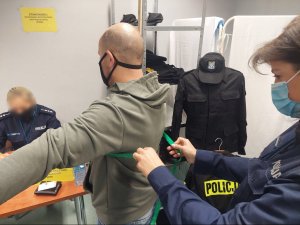 Na zdjeciu policjantka dokonuje pomiaru rezerwisty przed wydaniem umundurowania