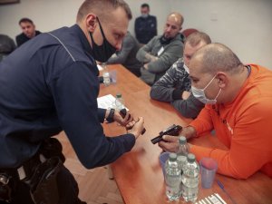 Na zdjęciu policjant w trakcie objaśniania rezerwitom budowy broni krótkiej