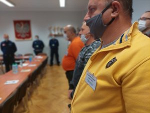 Zbliżenie na identyfikator służbowy jednego z rezerwistą. Na zdjęciu widać stojących w szeregu rezerwistów, w tle stoją policjanci