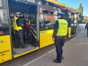 Na zdjęciu widać policjantkę z drogówki która weszła do autobusu w celu przeprowadzenia kontroli w związku z obowiązkiem zakrywania ust i nosa. Przed autobusem widac drugiego policjanta asekurującego mundurową