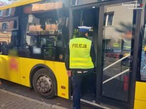 Na zdjęciu policjant z drogówki podczas wchodzenia do autobusu w celu przeprowadzenia kontroli pod katem przestrzegania obostrzeń