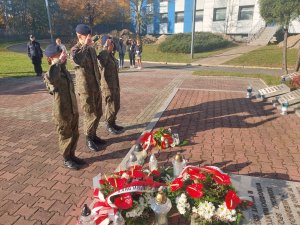 Na zdjeciu troje uczniow w poczcie honorowy podczas oddwania honoru przy Grobie Policjanta Polskiego.