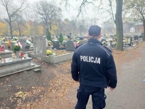 Na zdjeciu policjant w trakcie obserwacji sytuacji na cmentarzu podczas Święta Zmarłych