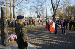 Na zdjęciu wiadac dwie kadetki stojące przy pomniku Powstańców Śląskich, na drugim planie widać jeden z pocztów ze sztandarem podaczas zatrzymania się przed pomnikiem