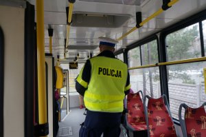 Na zdjęciu widać policjanta wewnątrz tramwaju w trakcie prowadzenia kontroli stosowania się do obostrzeń przed podróżnych