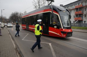 Na zdjęciu widać policjanta zmierzającego do tramwaju w celu przeprowadzenia kontroli stosowania się przed podróżnych do obostrzeń