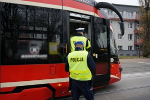 Na zdjęciu widac policjantów wchodzących do tramwaju w celu przeprowadzenia kontroli stosowania się do obostrzeń przed podróżnych