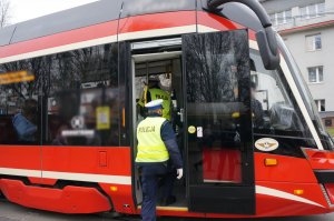 Na zdjęciu widac policjantów wchodzących do tramwaju w celu przeprowadzenia kontroli stosowania się do obostrzeń przed podróżnych